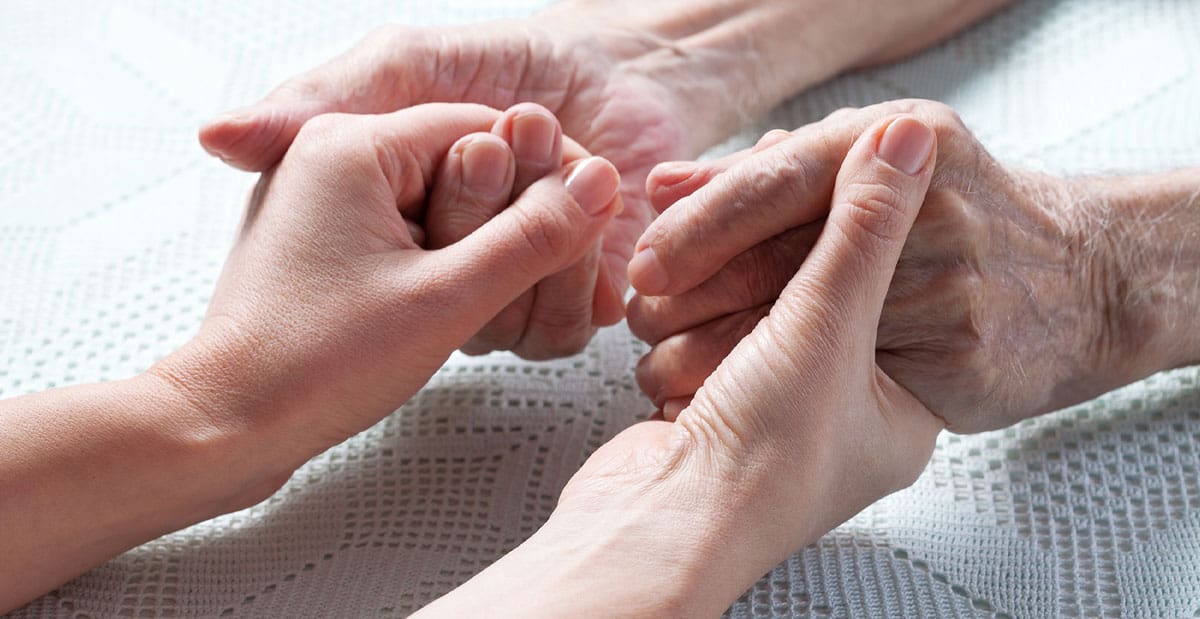 Two people holding hands on a bed